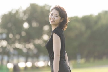 Deniz kenarındaki bir parkta siyah elbiseli Asyalı genç bir kadın.