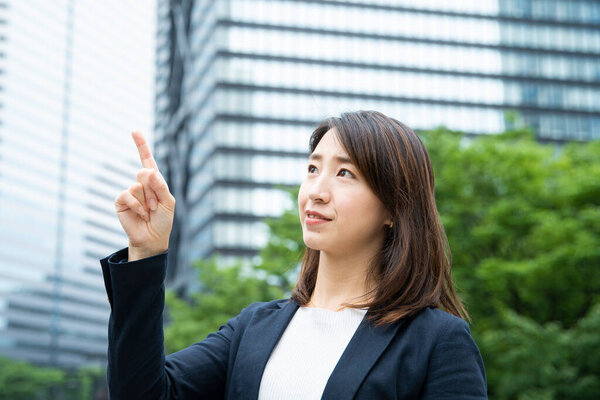 Asian business woman pointing up with index finger in business district