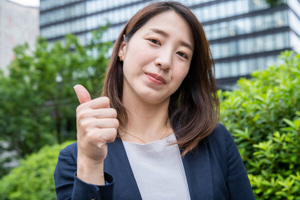 Asian (Japanese) young female office worker supporting by thumb up