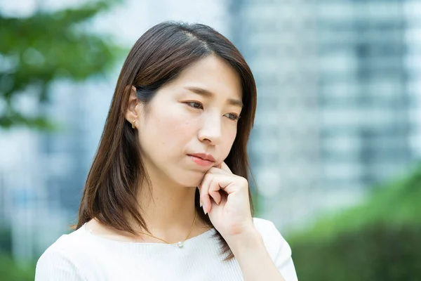 An Asian (Japanese) young female employee with a troubled expression