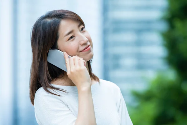 Asian female business person contacting using a smartphone at outdoors