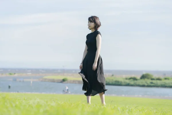 海のそばの公園で黒い服を着たアジア系の若い女性 — ストック写真
