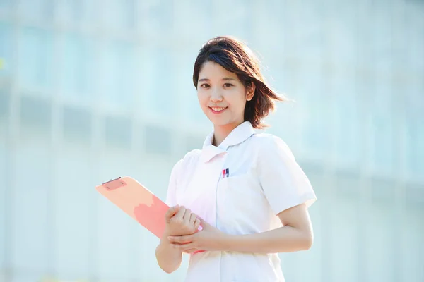 Portrait of an Asian (Japanese) female nurse showing a smile outdoors