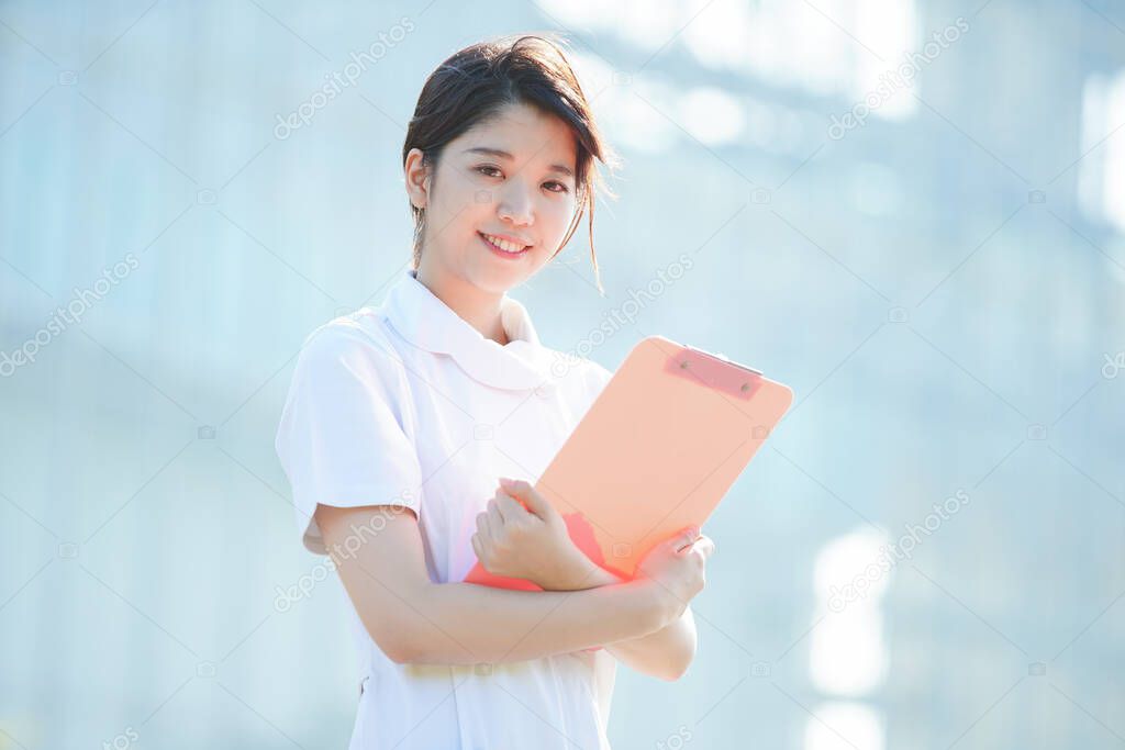 Portrait of an Asian (Japanese) female nurse showing a smile outdoors