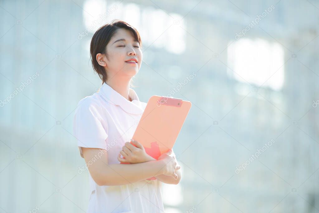 Portrait of an Asian (Japanese) female nurse showing a smile outdoors