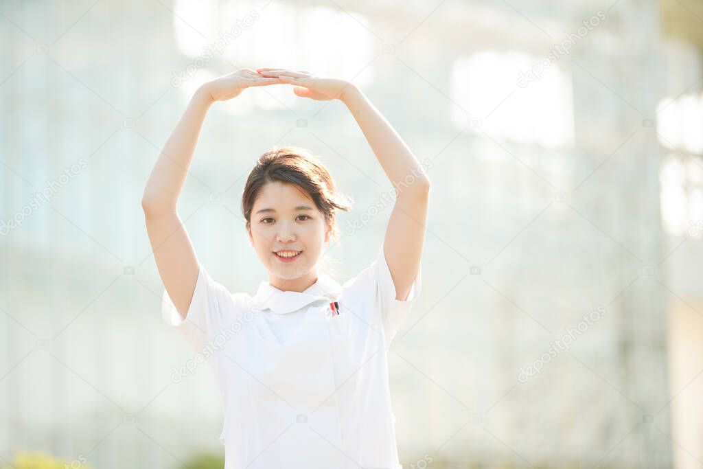 Asian (Japanese) female nurse with hands rounded and showing OK sign