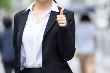 Asyalı (Japonca) genç bayan ofis çalışanı başparmağıyla destekliyor