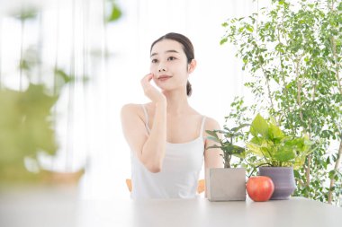 Parlak bir odada kendi cildini yapan Asyalı genç bir kadın.