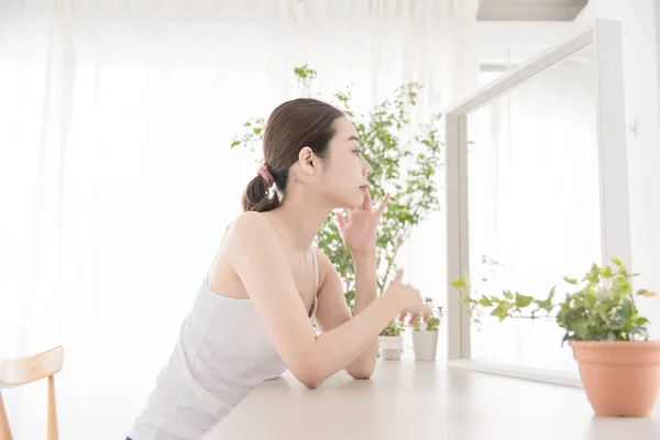 アジア系の若い女性が明るい部屋で自分のスキンケアをしている — ストック写真