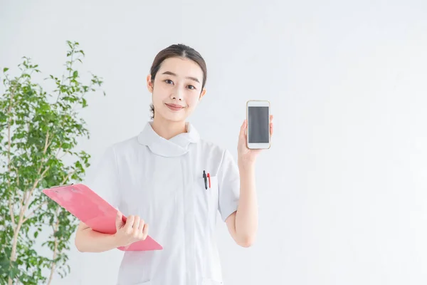 Asyalı Japonca Kadın Hemşire Gülümseyerek Akıllı Telefon Ekranı Gösteriyor — Stok fotoğraf