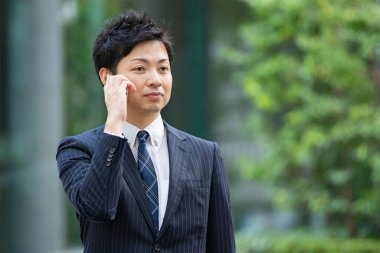 Bir iş bölgesinin caddesinde akıllı telefon kullanarak iletişim kuran Asyalı bir işadamı