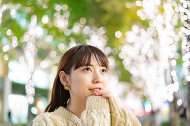Bir Asyalı (Japon) genç bir kadın gece şehrini renklendiren aydınlatmaları izliyor.