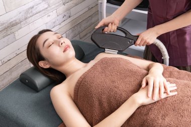 Saçlarını bir kuaförde koluna yaptıran Asyalı genç bir kadın.