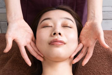 Asyalı kadın hastaya masaj yapan bir kadın pratisyen.