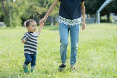 İki yaşındaki çocuk ve annesi güneşli bir günde parkta oynuyorlar.
