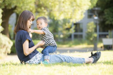 İki yaşındaki çocuk ve annesi güneşli bir günde parkta oynuyorlar.