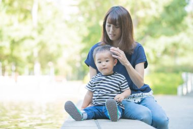 İki yaşındaki çocuk ve annesi güneşli bir günde parkta oynuyorlar.