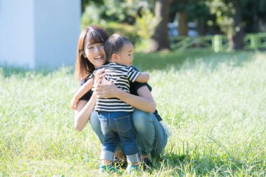 İki yaşındaki çocuk ve annesi güneşli bir günde parkta oynuyorlar.