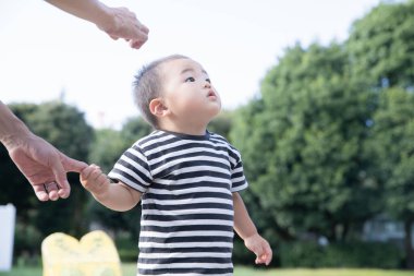 İki yaşındaki çocuk ve annesi güneşli bir günde parkta oynuyorlar.