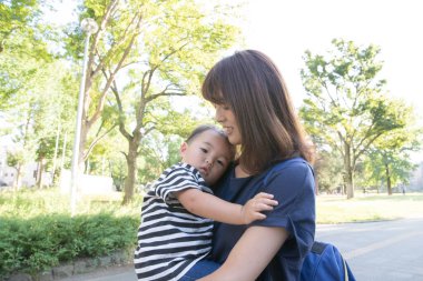 İki yaşındaki çocuk ve annesi güneşli bir günde parkta oynuyorlar.