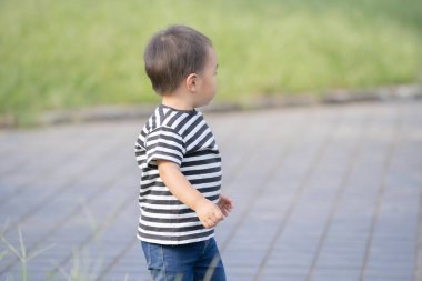 İki yaşındaki çocuk ve annesi güneşli bir günde parkta oynuyorlar.