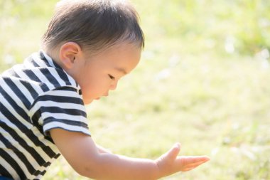 İki yaşındaki çocuk ve annesi güneşli bir günde parkta oynuyorlar.