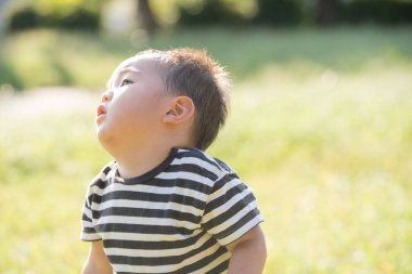İki yaşındaki çocuk ve annesi güneşli bir günde parkta oynuyorlar.