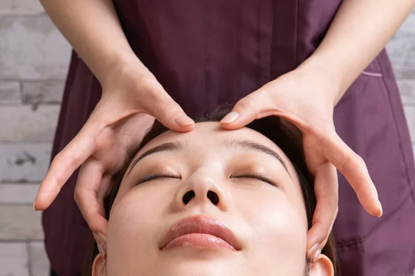 アジア女性患者の顔をマッサージする女性開業医 — ストック写真