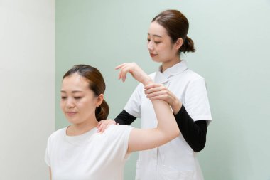 Asyalı kadın pratisyen doktor kadın hasta omuzları ve boynu.