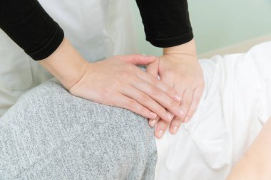 Asyalı kadın pratisyen kadın hasta beline ve soluna masaj yapıyor.