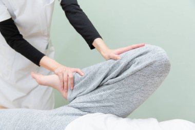 Asyalı kadın pratisyen kadın bir hastanın ayağına ve tabanına masaj yapıyor.