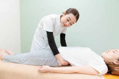 Asyalı kadın pratisyen kadın hasta beline ve soluna masaj yapıyor.