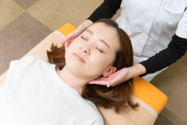 Asian female practitioner massaging shoulders and neck of female patient clipart