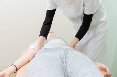Asyalı kadın pratisyen kadın hasta beline ve soluna masaj yapıyor.