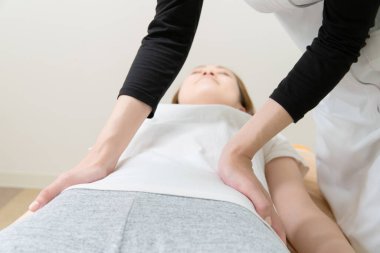 Asyalı kadın pratisyen kadın hasta beline ve soluna masaj yapıyor.