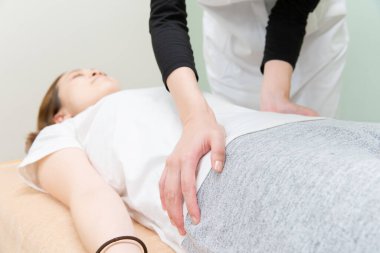 Asyalı kadın pratisyen kadın hasta beline ve soluna masaj yapıyor.
