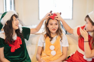 Asyalı genç kadınlar Noel kostümü giyip parti veriyorlar.