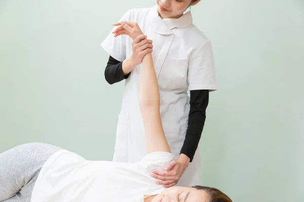 Asiatische Ärztin Massiert Schulter Und Arm Einer Patientin — Stockfoto