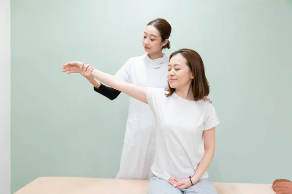 Asiatische Ärztin Massiert Schulter Und Arm Einer Patientin — Stockfoto