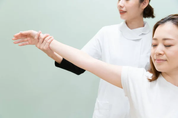 Asiatische Ärztin Massiert Schulter Und Arm Einer Patientin — Stockfoto