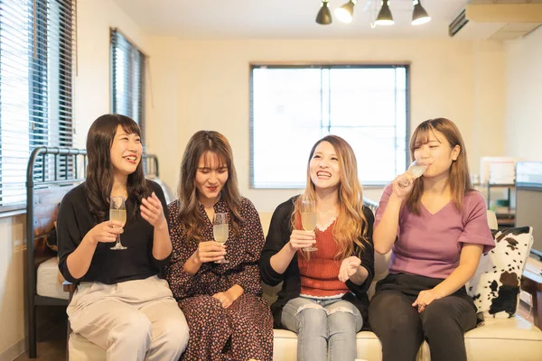 Four Asian young women toasting with champagne glasses at indoor party