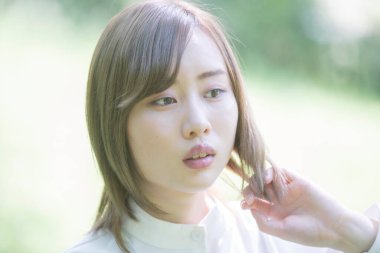 Parkta rahat bakışlarla yürüyen Asyalı genç bir kadın.