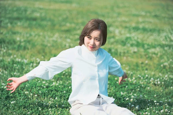 亚洲年轻女子在草地上表现出一种轻松的表情 — 图库照片