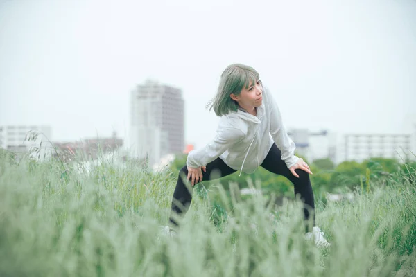 都市部の緑の空間で運動をストレッチアジアの若い女性 — ストック写真