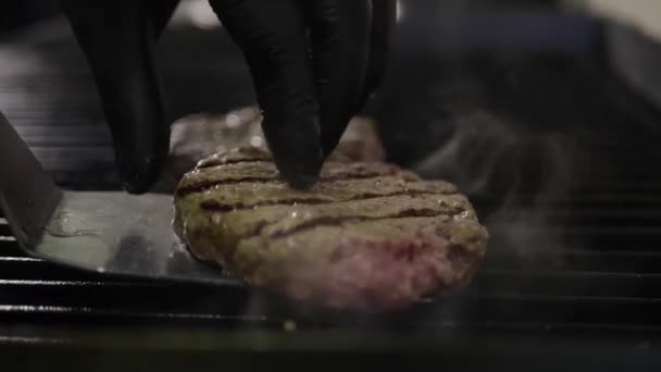 Carne sul fornello, fumo di fuoco, cottura di un hamburger e un cuoco di hamburger in cucina Filmato Stock