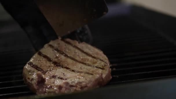 Carne sul fornello, fumo di fuoco, cottura di un hamburger e un cuoco di hamburger in cucina Video Stock