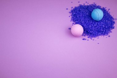 Bombalar ve deniz banyosu tuzu. Rahatlamak için lavanta. Soluk pembe arka planda dağ lavantası özü olan deniz tuzu kayması. Mavi ve pembe aromalı banyo bombaları. Mor ve pembe renklerde lakonik kompozisyon.