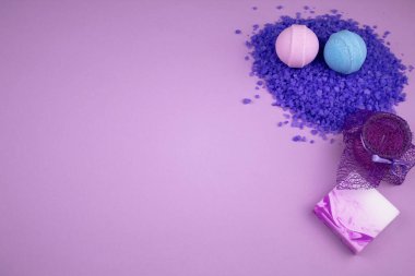 Lavanta banyosu, tuz ve mum. Soluk pembe arka planda dağ lavantası özü olan deniz tuzu kayması. Mavi ve pembe aromalı banyo bombaları. Lavanta mumu ve el yapımı sabun.