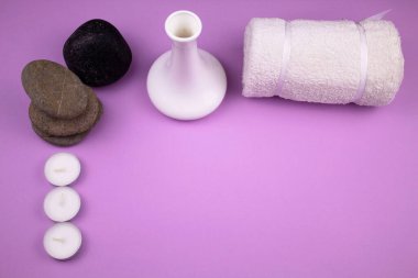 Aromaterapi ve taş masajı. Spa prosedürü için bir takım ögeler görüntünün iki tarafına yerleştirilmiştir. Yumuşak beyaz havlu, kokulu mumlar. Üç gri taş ve bir büyük siyah taş. Sağlık veren mineraller. Metin için büyük kutu.