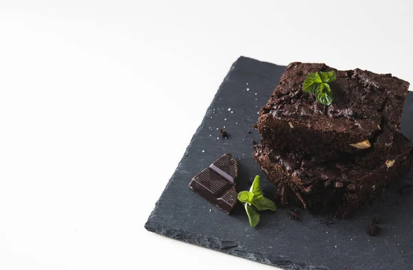 Cevizli browni parçalarını levha ve beyaz arka planda, ceviz, çikolata ve nane yapraklarıyla süslenmiş, fotokopi alanı ile